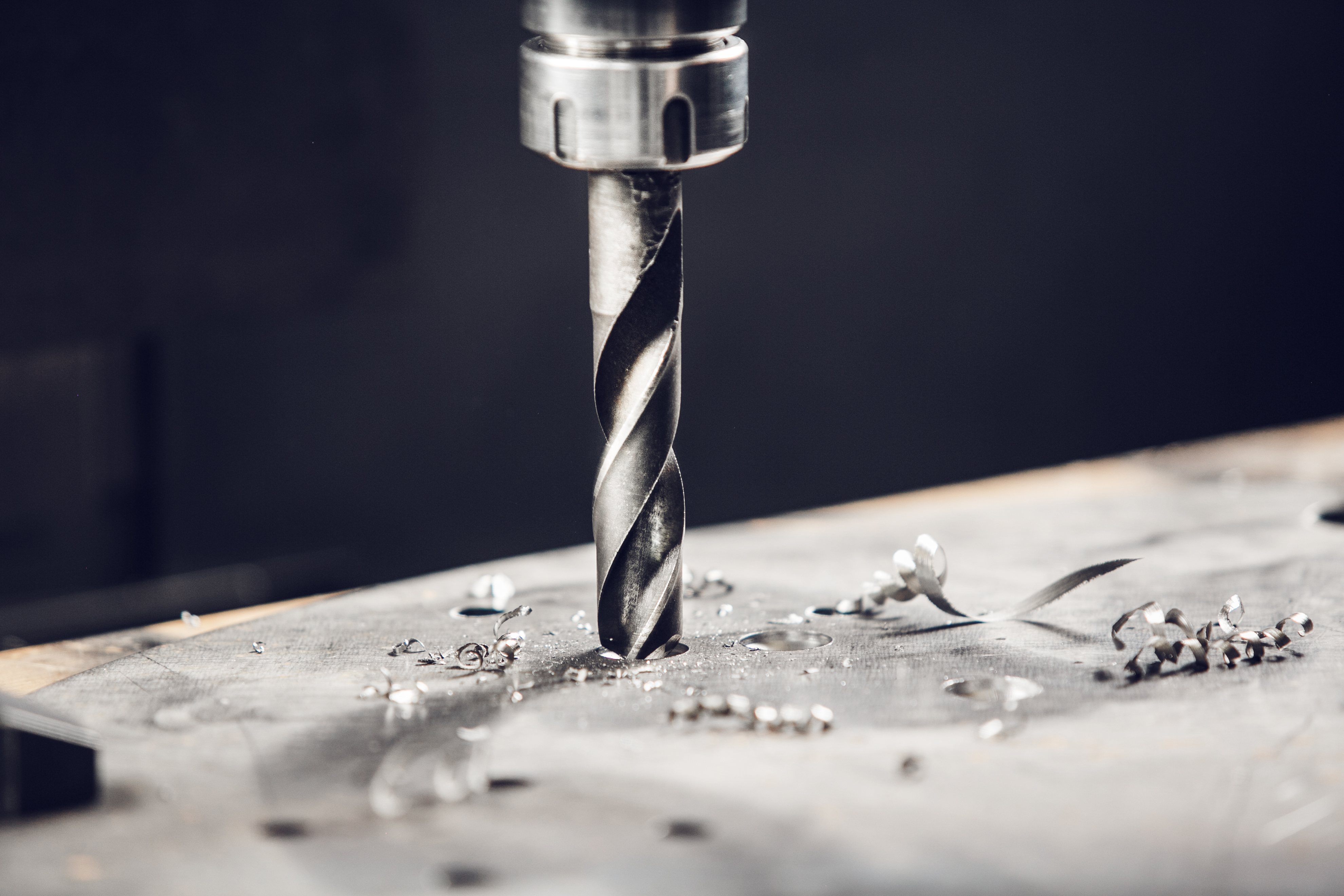 A twist drill boring a hole in a steel plate, spiral chips around it